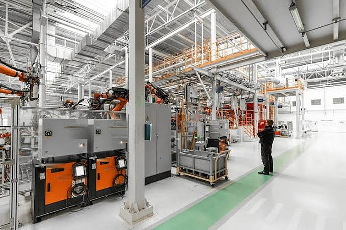 Factory floor with robotic welding cells and control cabinets